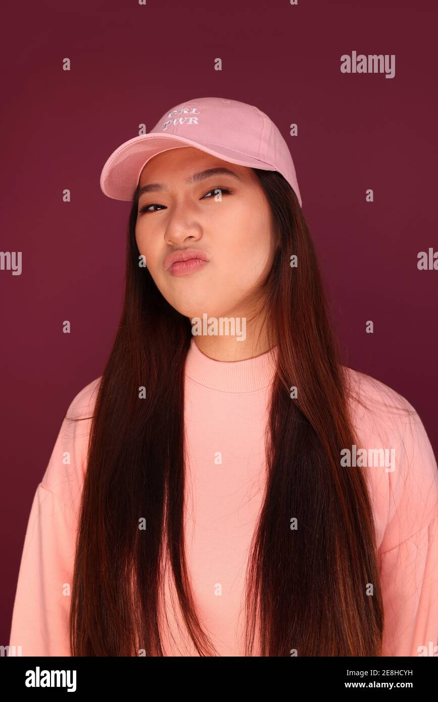 Portrait of happy young asian Woman in the studio wearing pink clothes over garnet background Stock Photo