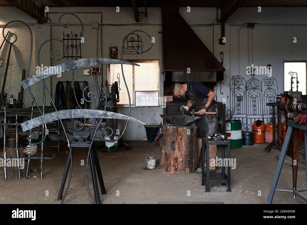 Side view of unrecognizable concentrated young male blacksmith in ...