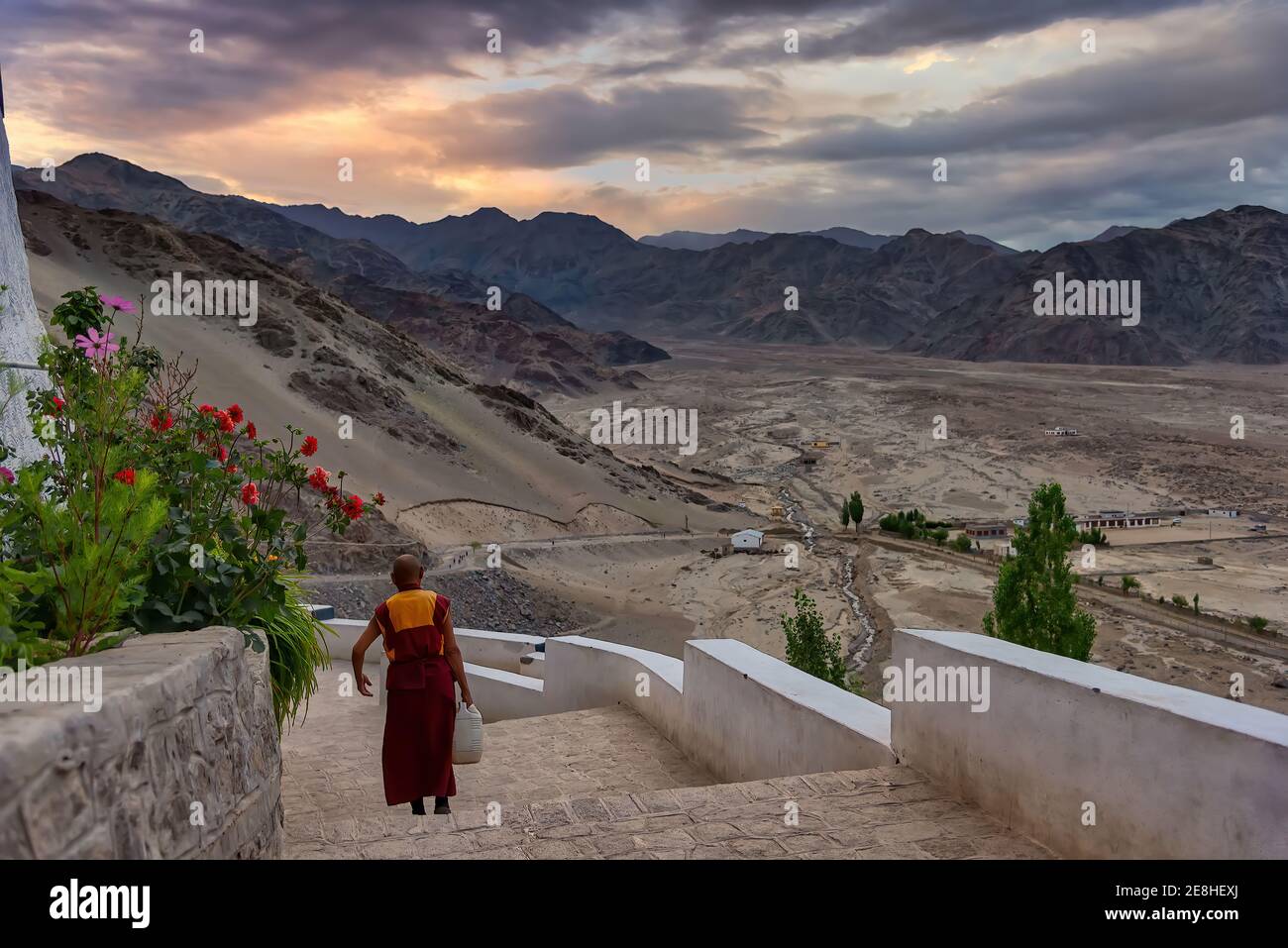 Thikse, India - August 24, 2015: An elder monk at goes down the stairs of Thikse Monastery at sunrise. Thikse Monastery is located on top of a hill Stock Photo