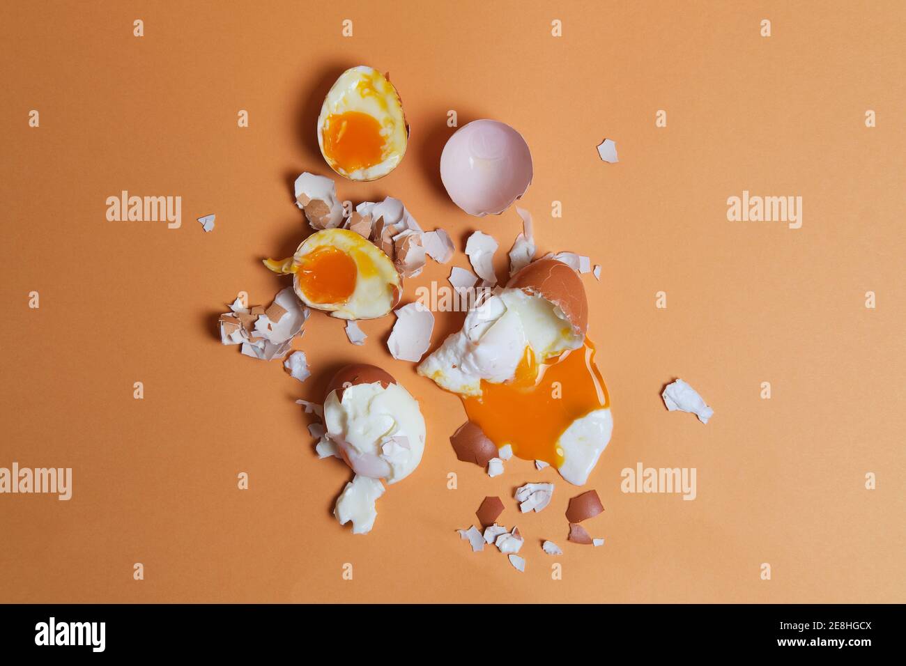 Top view of soft boiled chicken eggs and eggshell scattered on peach background in studio Stock Photo