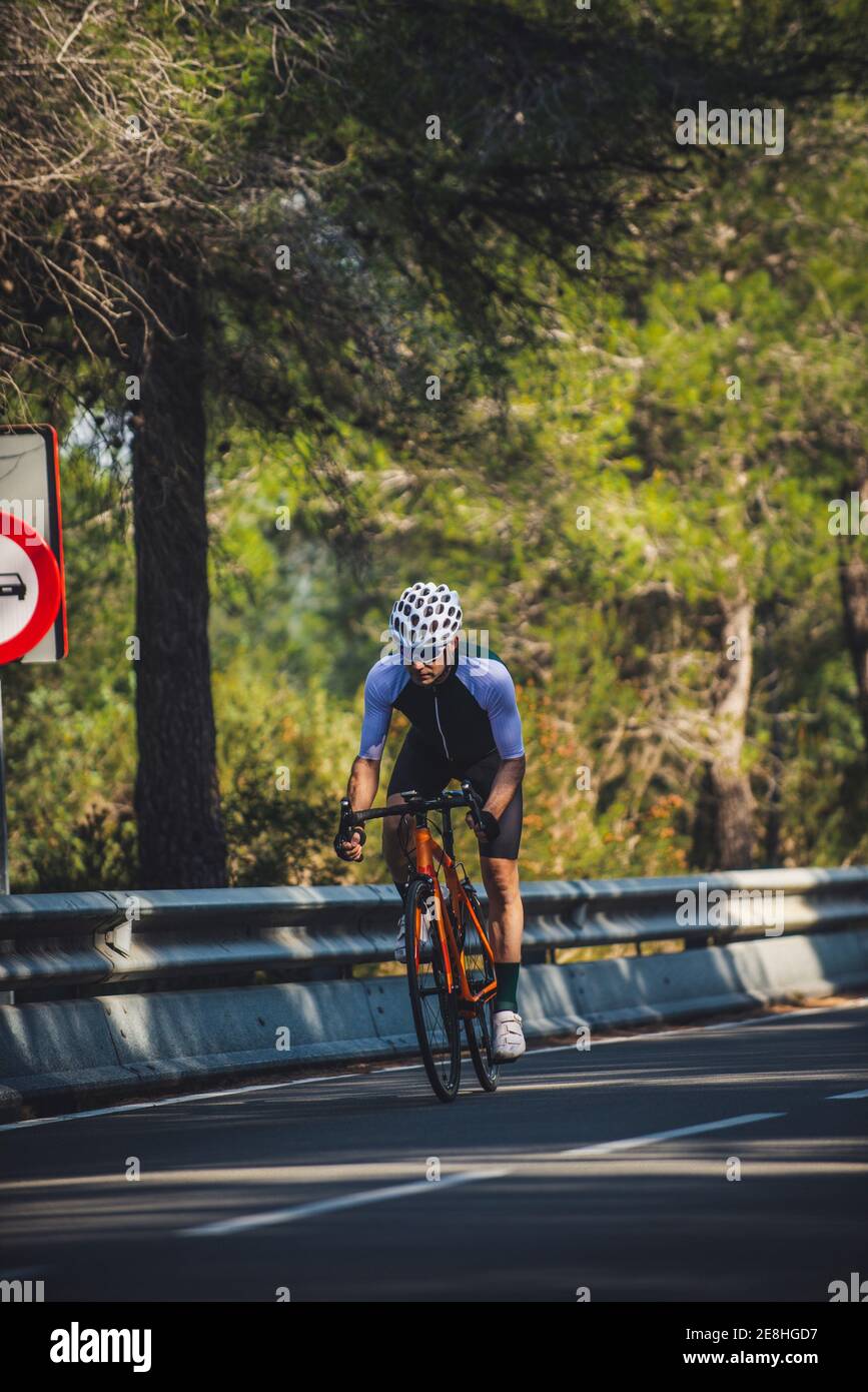 Full body of young sportsman in activewear and helmet riding bicycle on ...