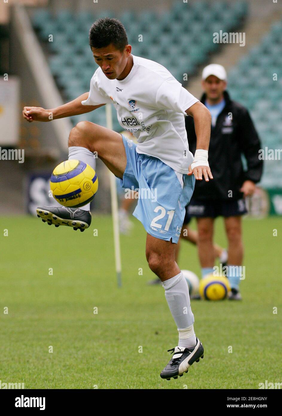 Sydney FC Japanese soccer star Kazuyoshi 'Kazu' Miura (L) is watched by a trainer (R) as he controls the ball during a training session in Sydney November 24, 2005. Miura will play a total of four matches before joining Sydney FC's FIFA Club World Championship competition in Japan from December 11-18. REUTERS/Will Burgess Stock Photo