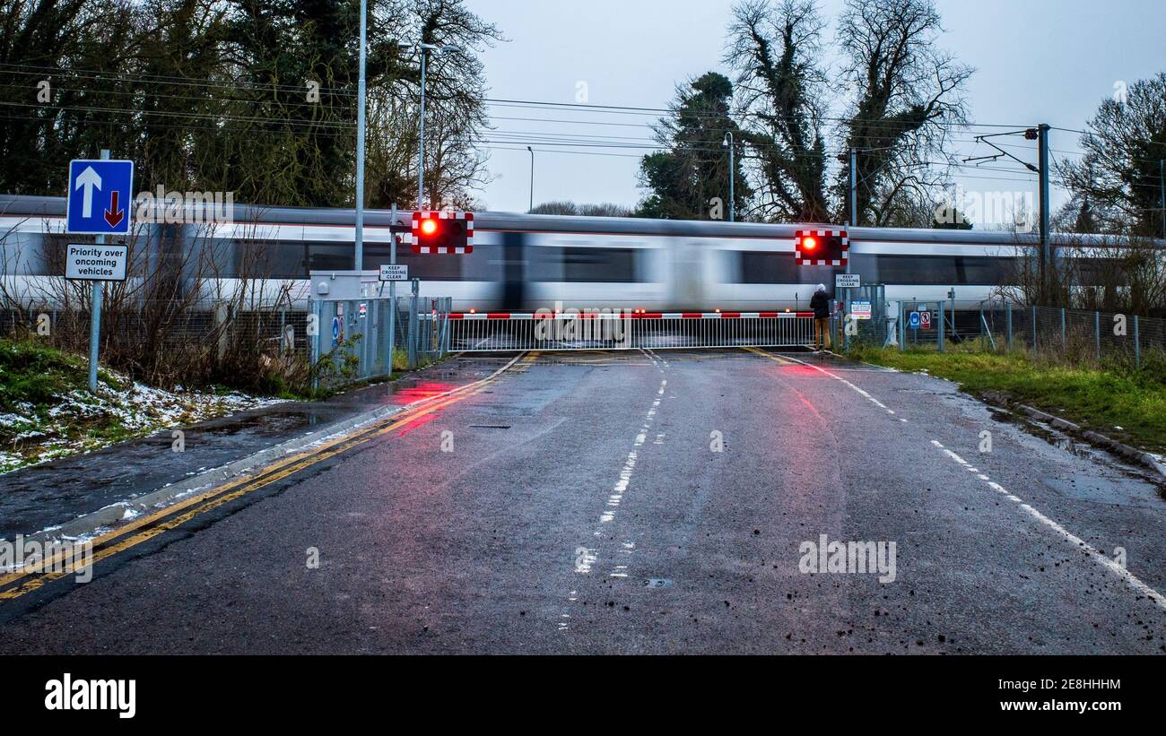 Greater Anglia train passes through a level crossing in mid winter, UK Railway Level Crossing near Cambridge. Closed Level Crossing. Stock Photo