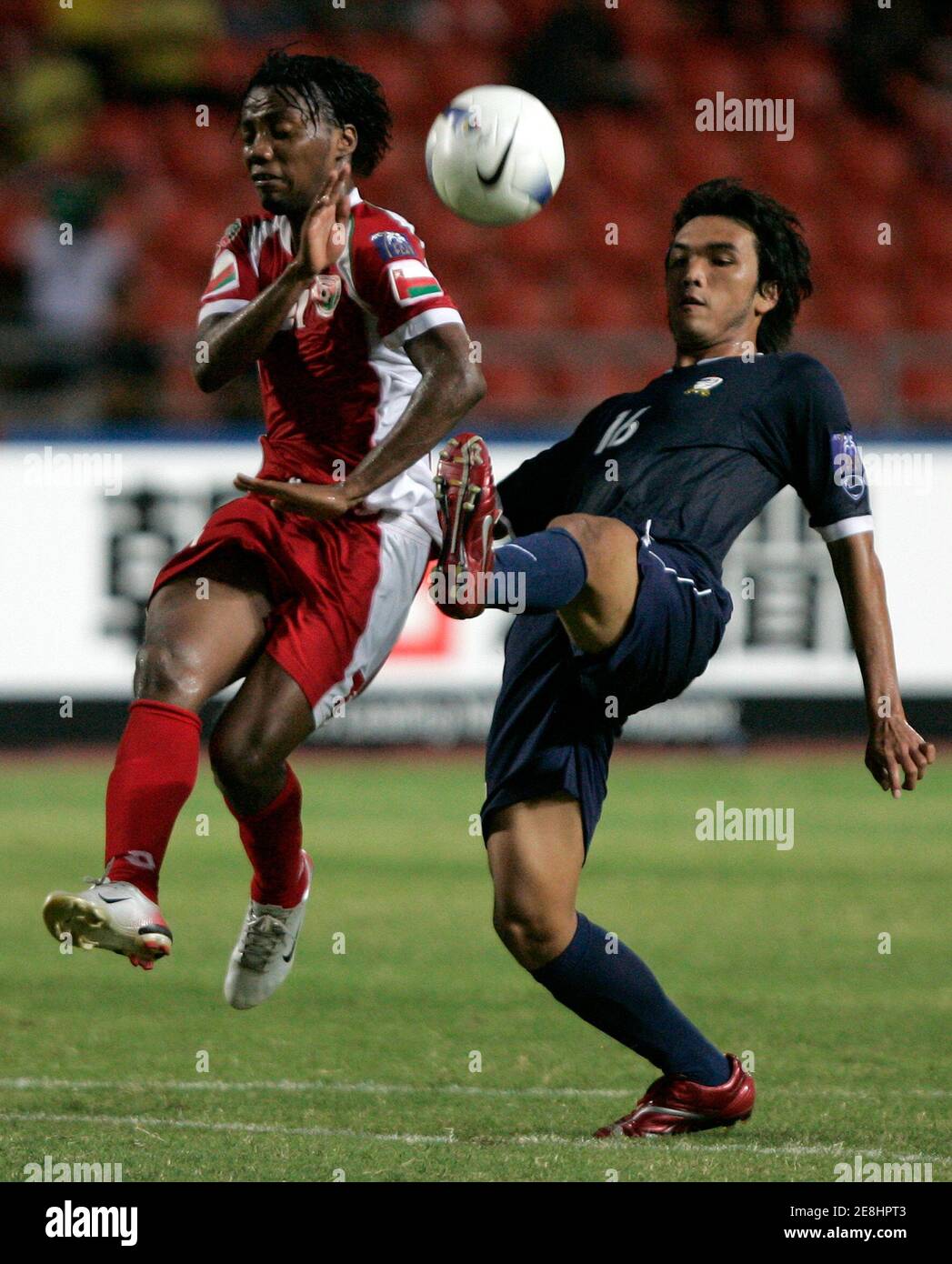 Thailand's Kiatprawut Saiwaeo (R) kicks the ball past Oman's Ahmed Hadid during their AFC Asian Cup Group A match at Rajamangala Stadium in Bangkok July 12, 2007. Thailand defeated Oman 2-0.  REUTERS/Chaiwat Subprasom  (THAILAND) Stock Photo