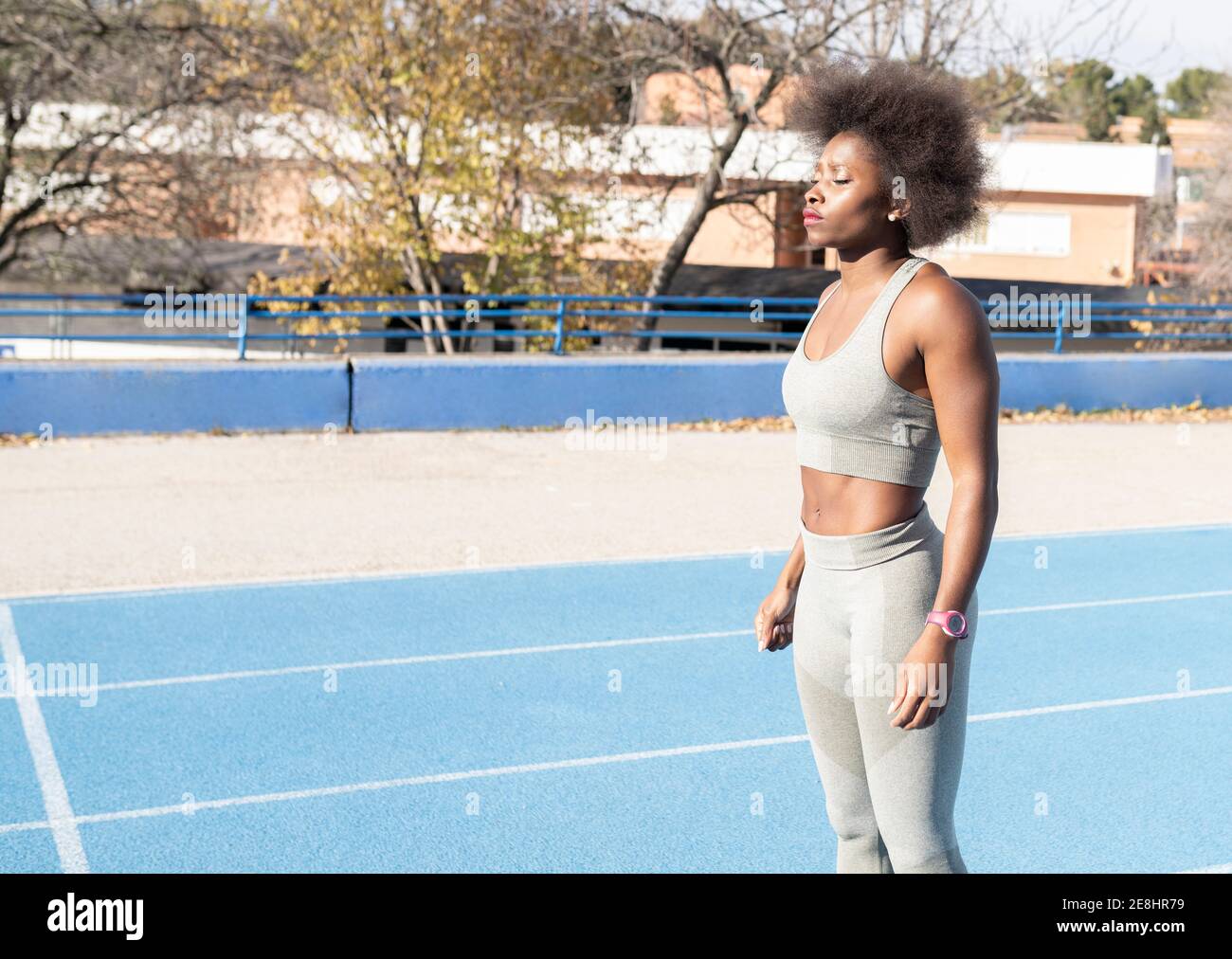 Side view of concentrated African American runner standing on track and preparing for race with closed eyes at stadium Stock Photo