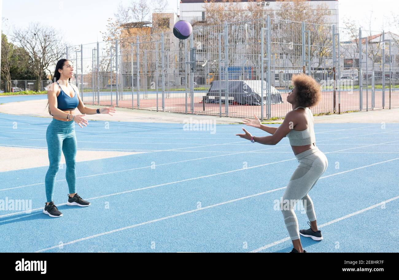 Multiracial muscular female athletes throwing medicine ball while