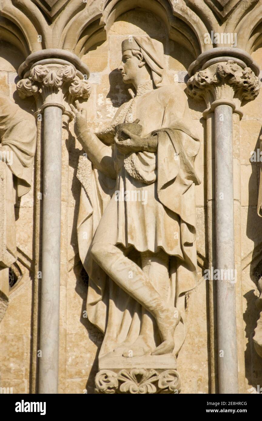 Stone sculpture of Saint Damian holding a pestle and mortar. Sculpted in 1868 by James Redfern and displayed on the West Front of Salisbury Cathedral. Stock Photo