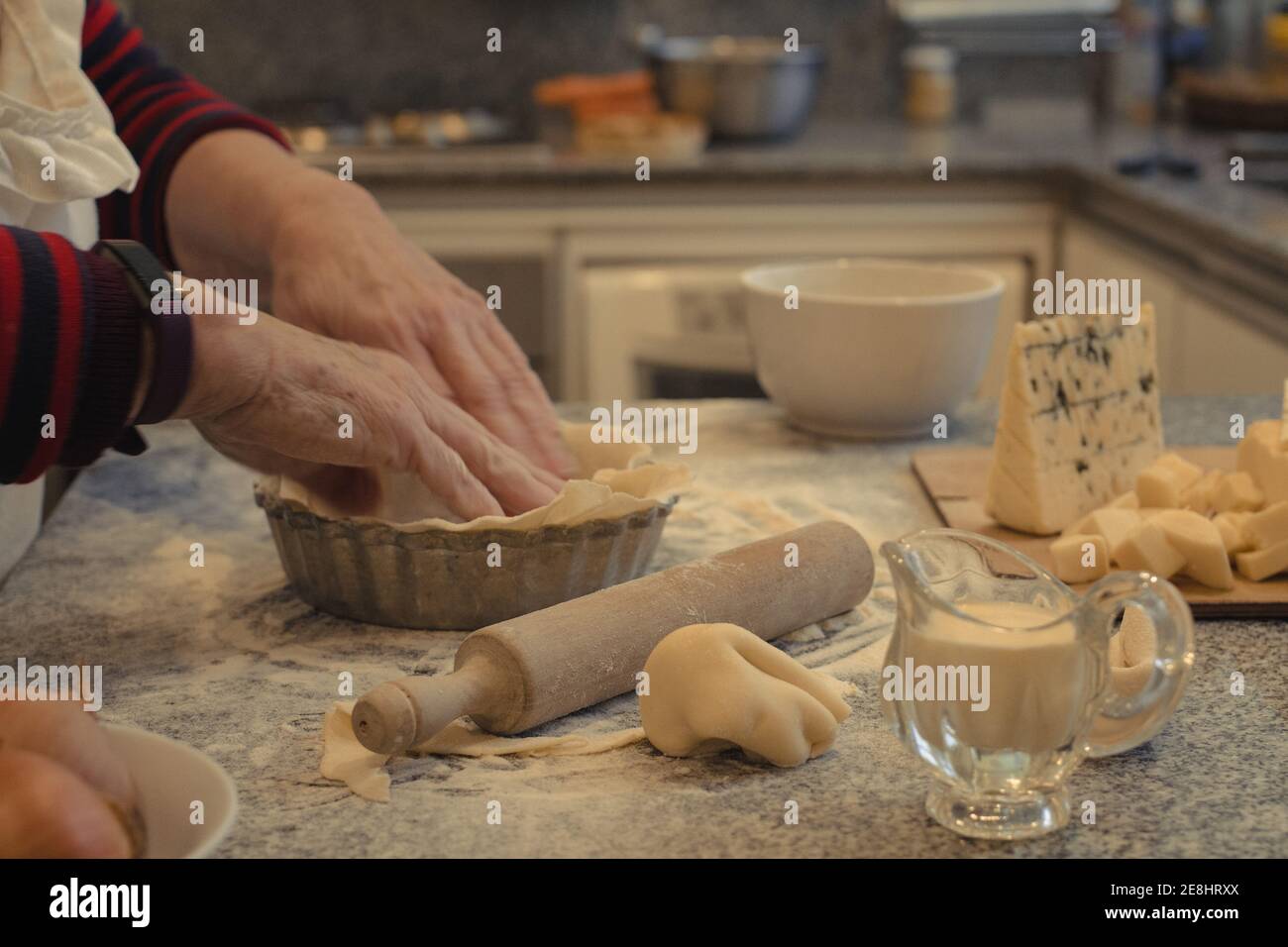 Crop anonymous chef with pastry crust above table with baking dish and ...