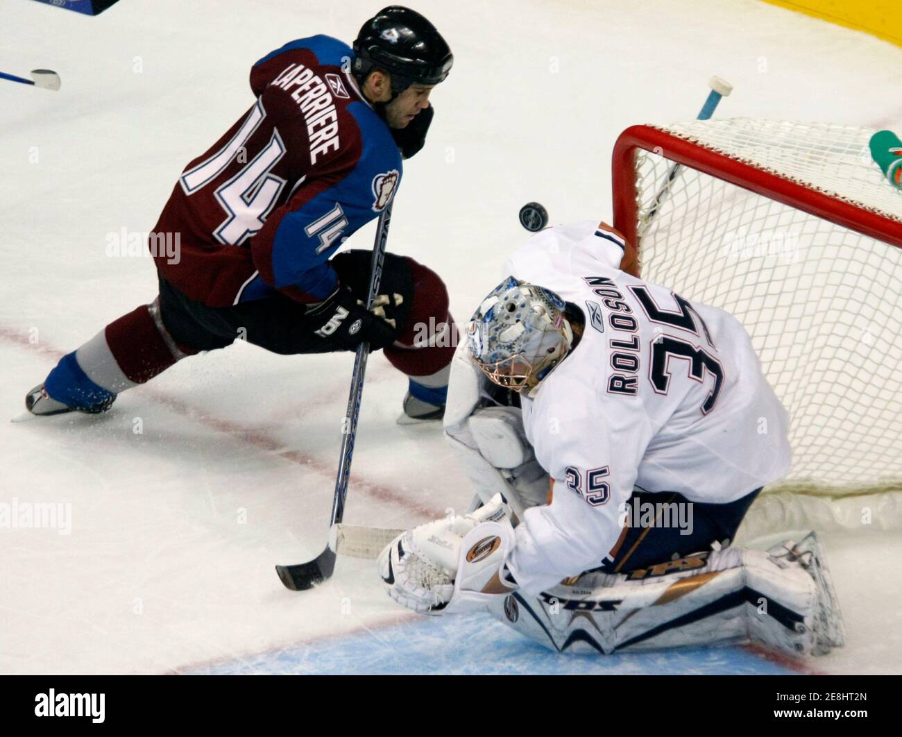 Colorado Avalanche winger Ian Laperriere (L) nearly rolls the puck over the shoulder of Edmonton Oilers goaltender Dwayne Roloson in the third period of their NHL hockey game in Denver November 7, 2007. REUTERS/Rick Wilking (UNITED STATES) Stock Photo
