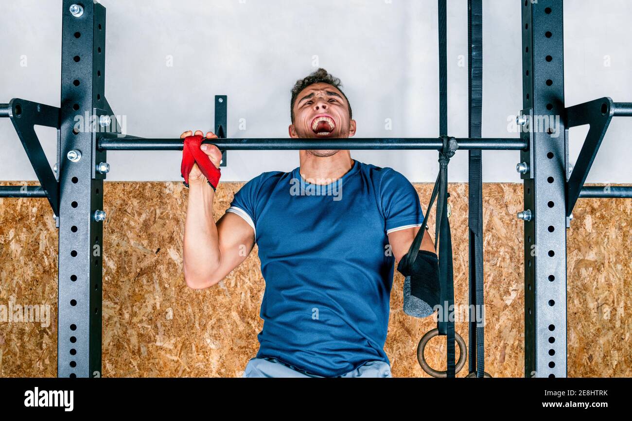 Young athlete handicapped sportsman training on horizontal bar during training in gym Stock Photo