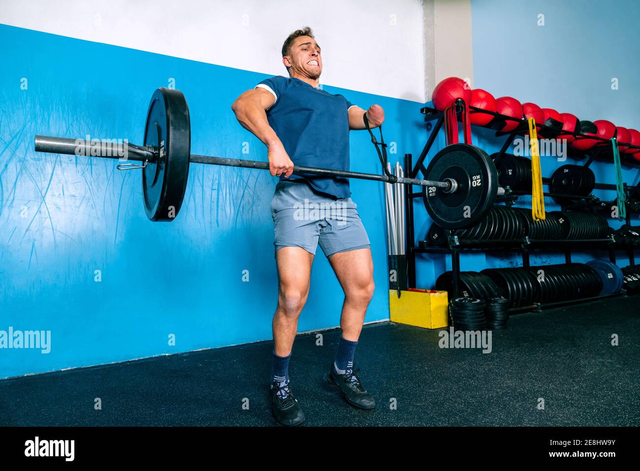 Powerful male athlete without hand lifting heavy weight during