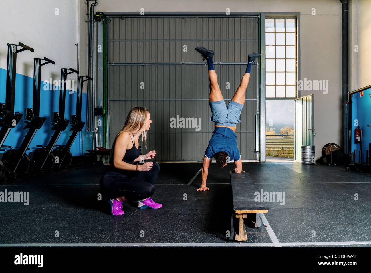 Young smiling female athlete training and helping anonymous handicapped ...