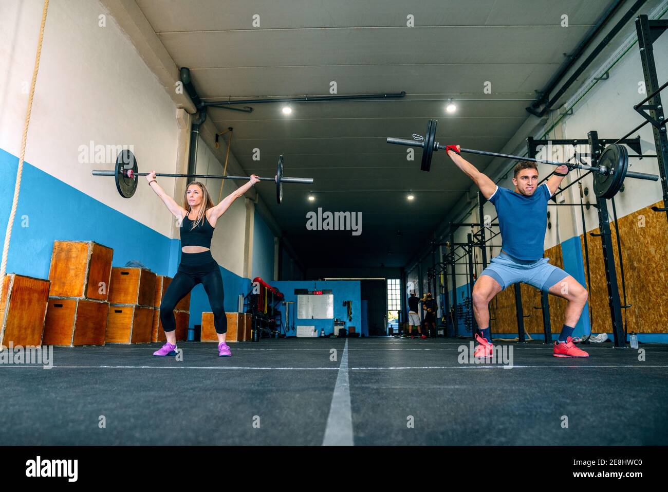 From below powerful sportsWoman with handicapped male athlete lifting heavy weights and looking