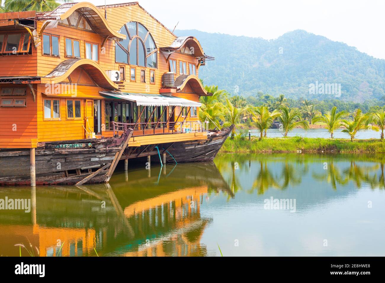 Tropical landscape. Wooden house in the form of a boat on the ocean with a view of the mountains. Travel and tourism in Asia. Stock Photo