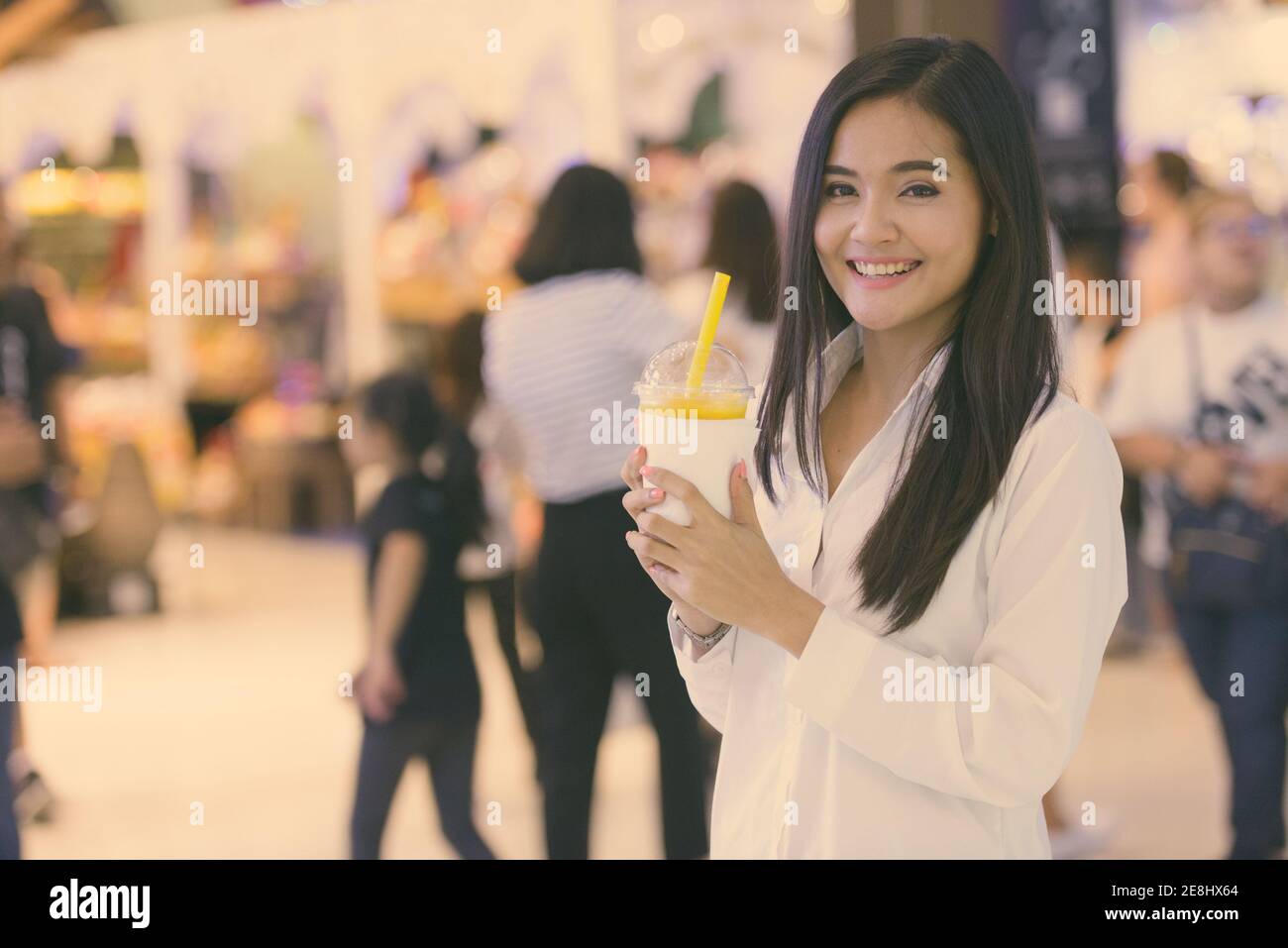 Beautiful Asian woman drinking juice in shopping mall Stock Photo