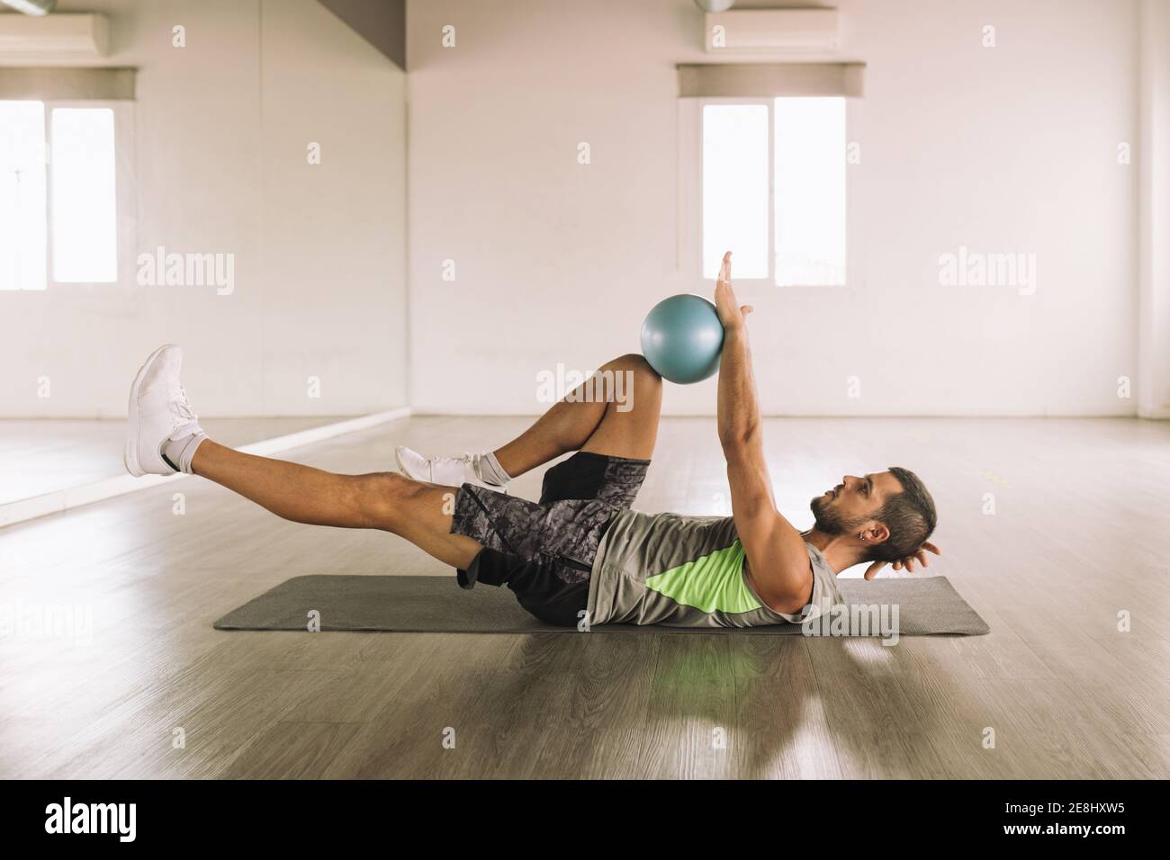 Side view of determined muscular young sportsman in activewear doing Leg  Crunch exercise with medicine ball while lying on mat during workout in  light Stock Photo - Alamy