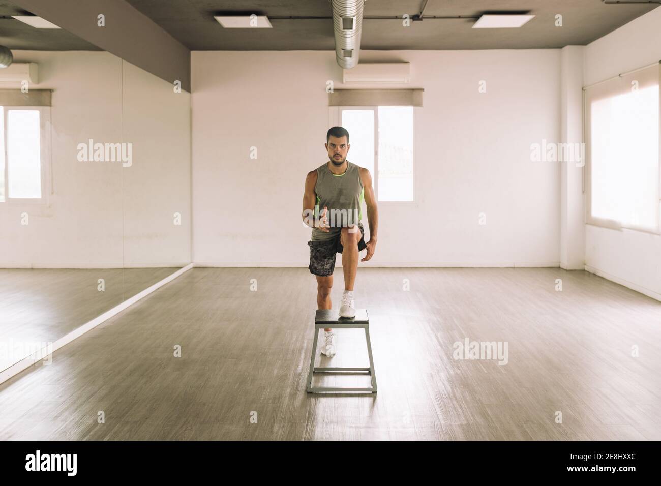 Front view of serious young fit athletic male in activewear doing One