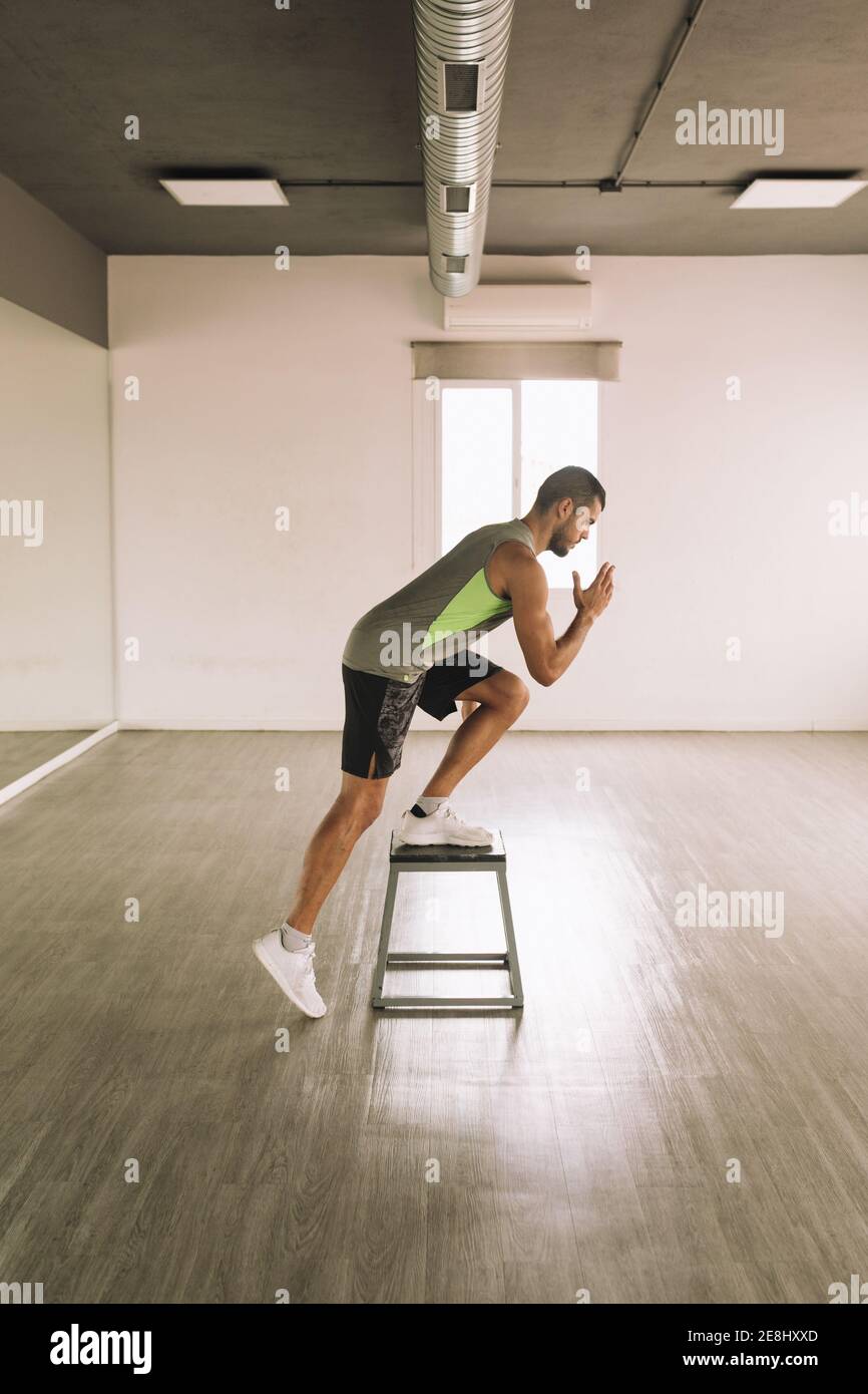 Side view of serious young fit athletic male in activewear doing One
