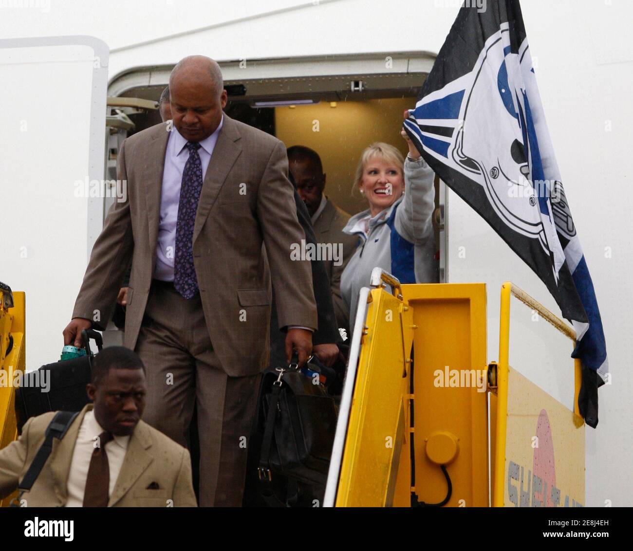 The NFL Indianapolis Colts head coach Jim Caldwell (C) and defensive backs coach  Alan Williams (bottom) disembark the team's charter as a flight attendant  waves a flag at Ft. Lauderdale airport in