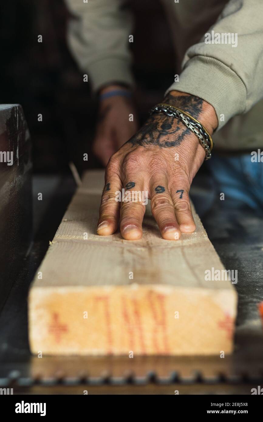 Unrecognizable crop male woodworker without a thumb processing piece of wood at workbench while working in joinery Stock Photo