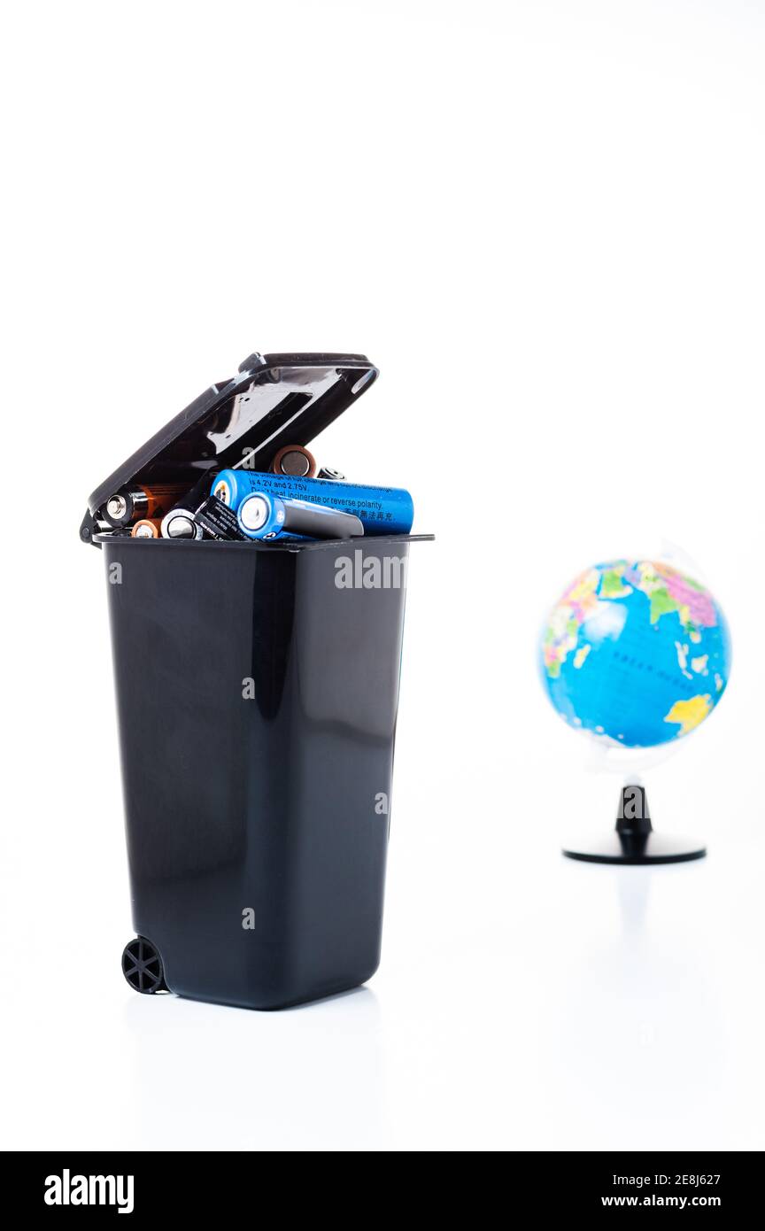 Garbage container with rubbish on the background of the globe. Land pollution. Vertical frame. Stock Photo