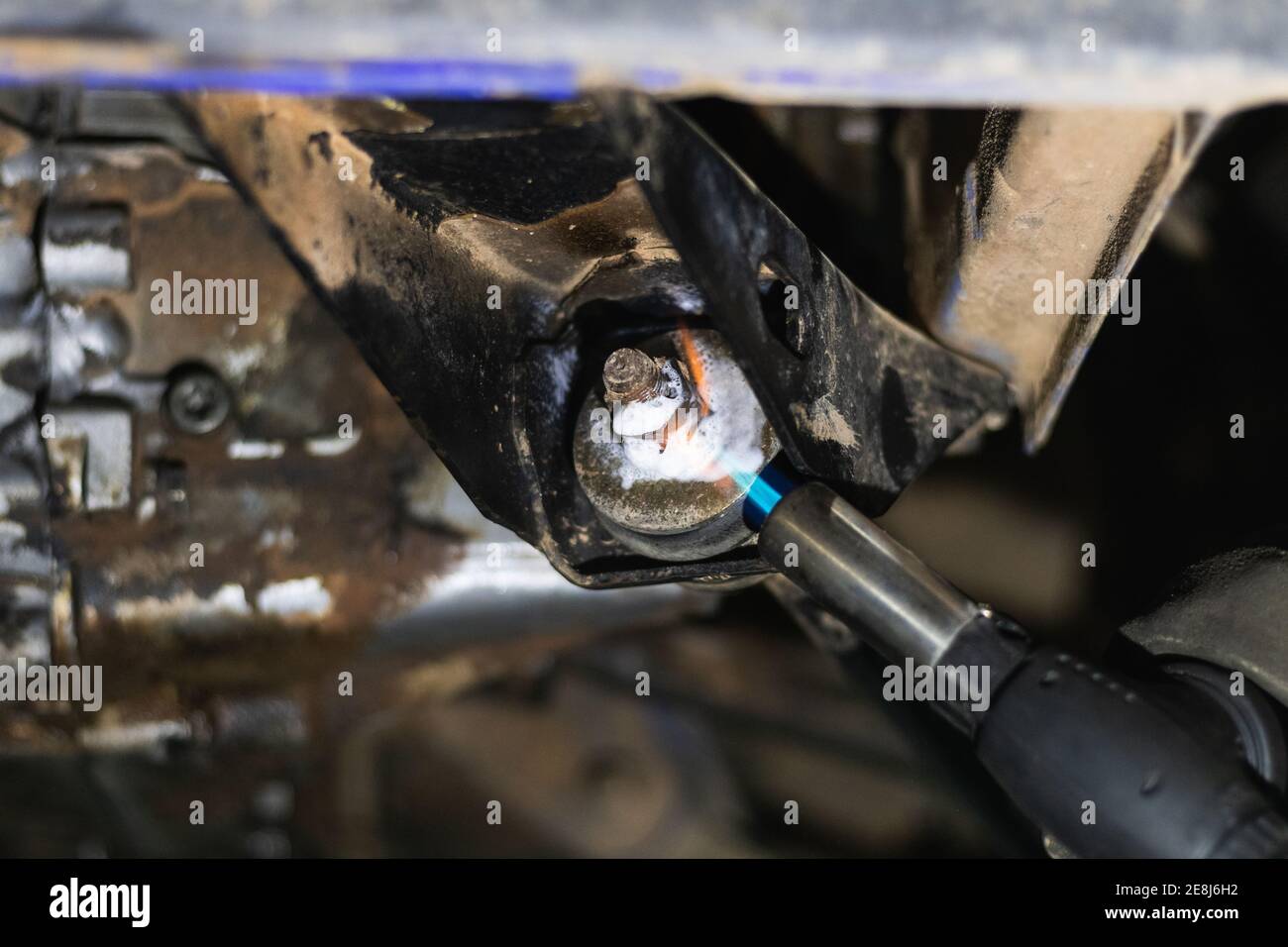 Back view of unrecognizable male auto mechanic torch while removing