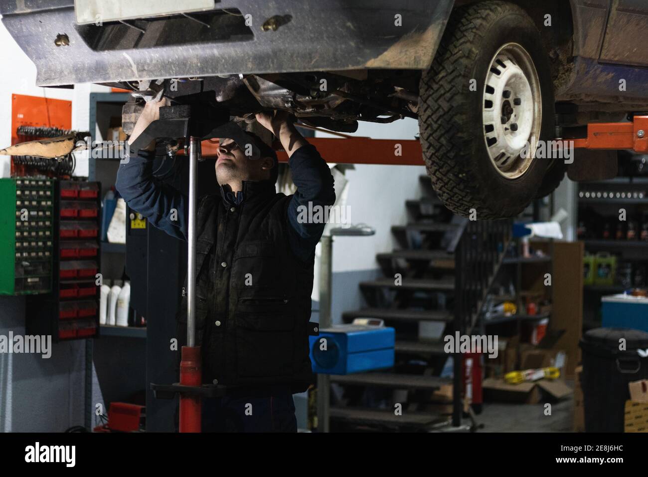 Male with auto torch while removing stripped lug nuts from car during