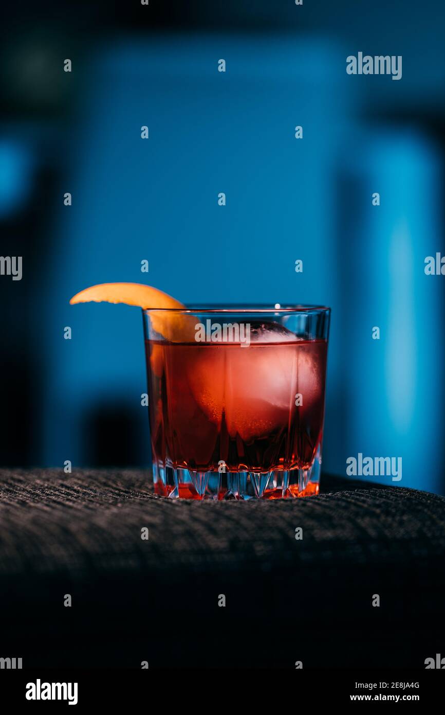 Glass of refreshing Negroni cocktail with bitter flavor and ice garnished with orange peel and