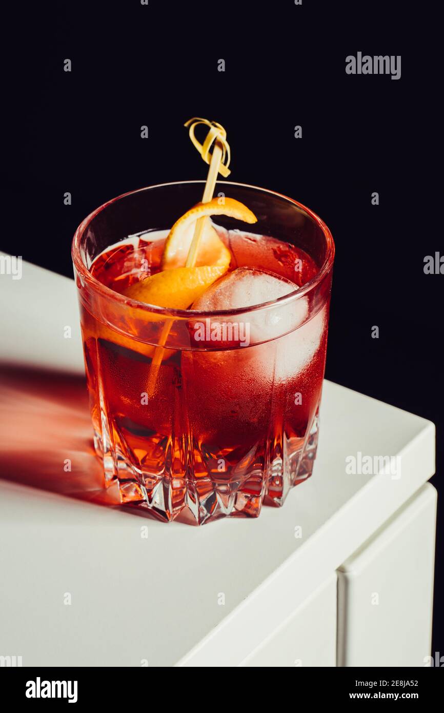 Glass of bitter alcoholic Negroni cocktail served with ice and orange