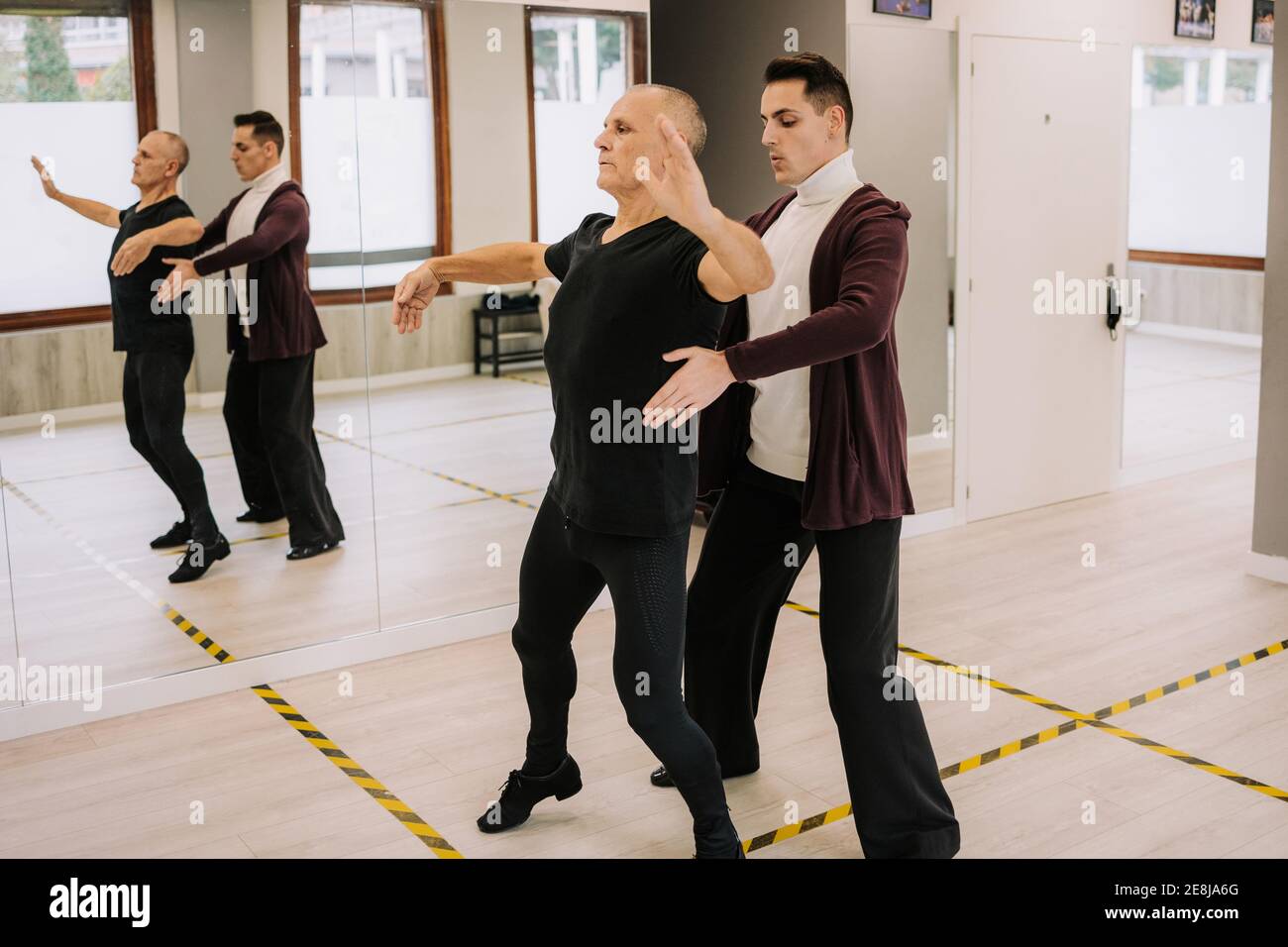 Side view of male instructor helping mature dancer with movement during ballroom dancing in