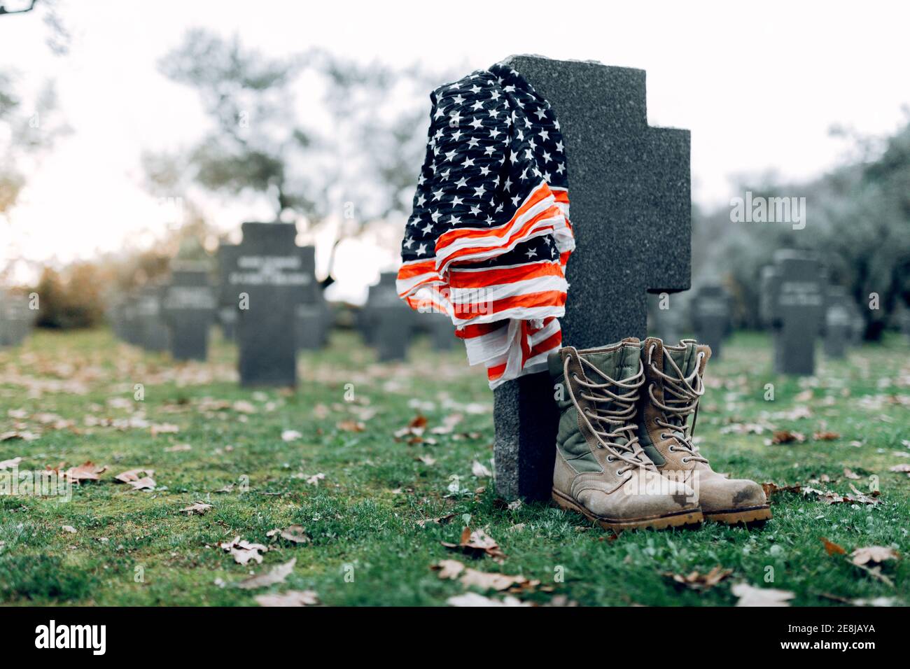 National American flag and army flag placed on gravestone in military cemetery on early autumn day Stock Photo