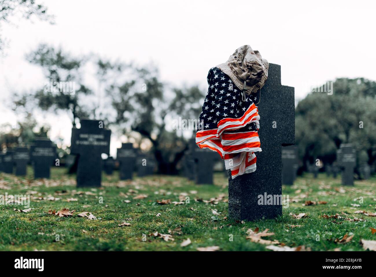 National American flag and army flag placed on gravestone in military cemetery on early autumn day Stock Photo