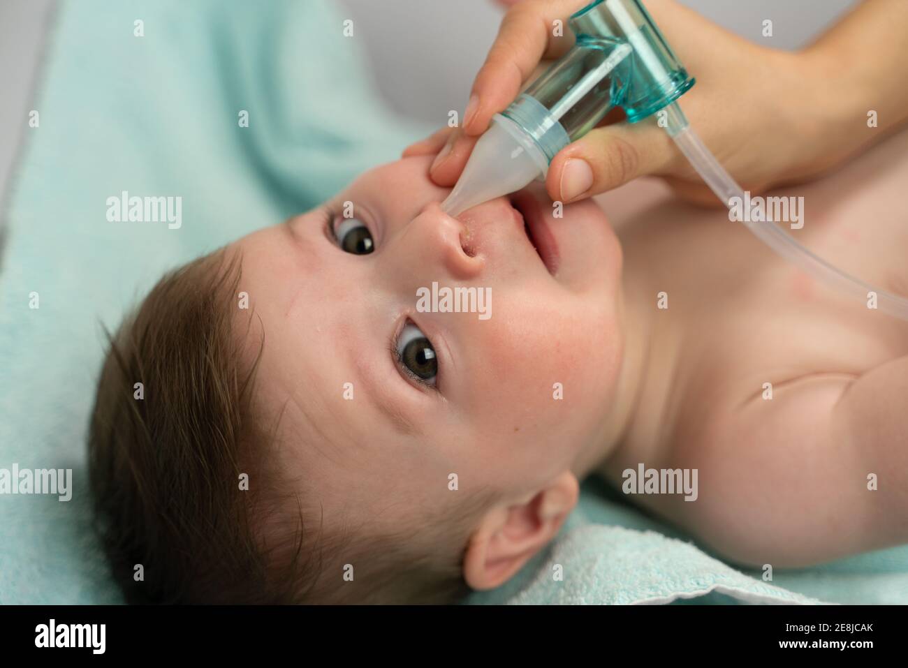 Crop caring mother placing suction machine into adorable baby nostril