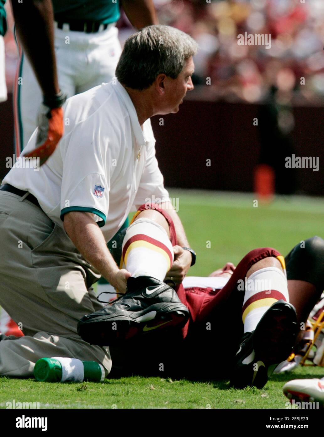 An unidentified member of the Washington Redskins medical team (L) looks at the severe ankle injury of Redskins' offensive tackle Jon Jansen in the first half of their NFL football game against the Miami Dolphins in Landover, Maryland September 9, 2007. Jansen left the game with the injury.   REUTERS/Gary Cameron  (UNITED STATES) Stock Photo