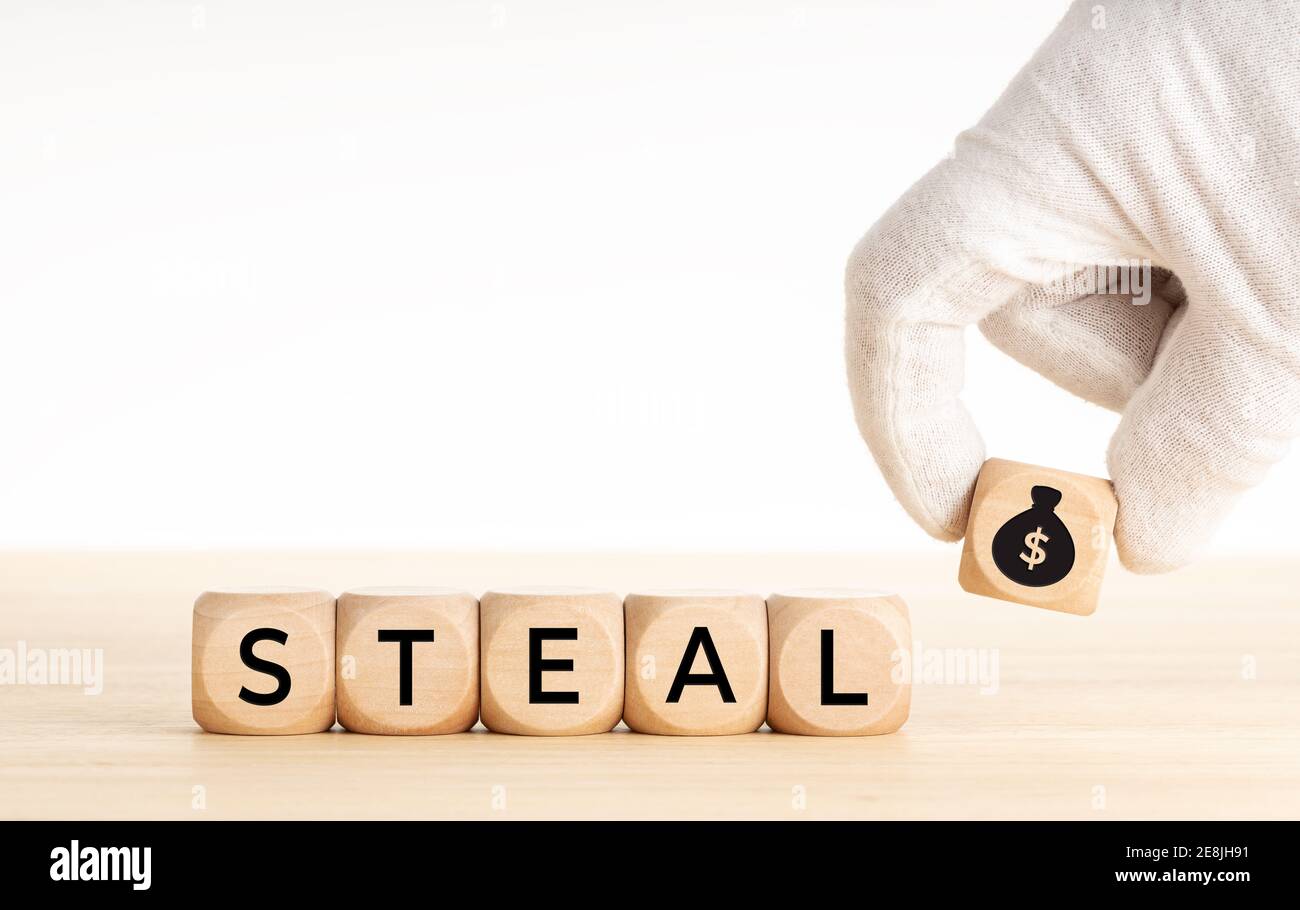 Steal concept. Hand picking a wooden block whit money bag icon and text on wooden dice. Copy space. White background Stock Photo
