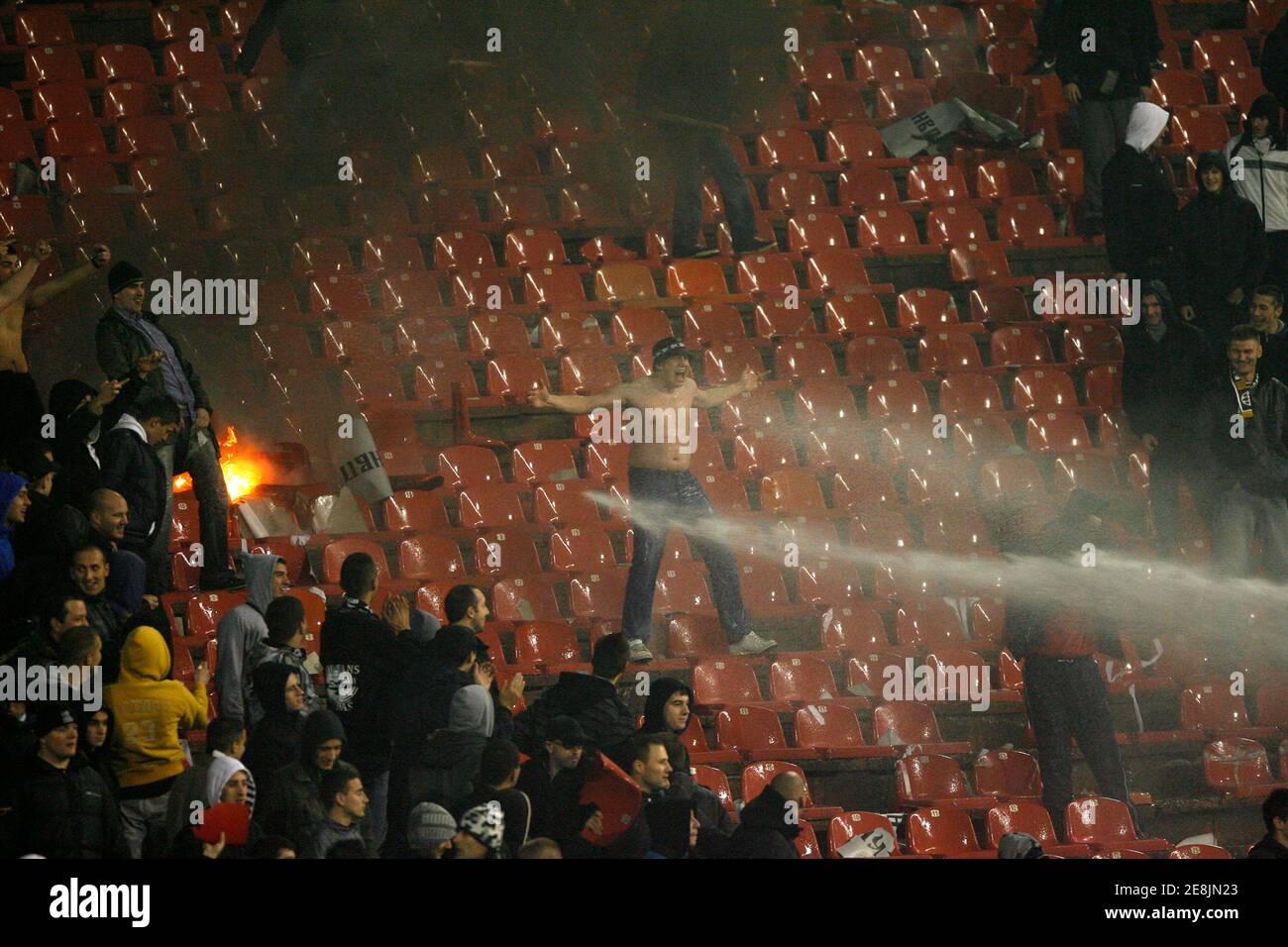 Firefighters work to extinguish fires burning in the stands during a Serbian first division soccer match between Red Star and Partizan in Belgrade November 28, 2009. Partizan won the match 2-1.  REUTERS/Ivan Milutinovic  (SERBIA SPORT SOCCER) Stock Photo