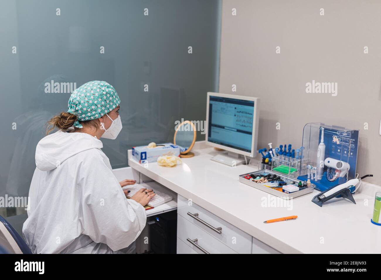 Female dentist using computer at office desk. Looking at the screen Stock Photo