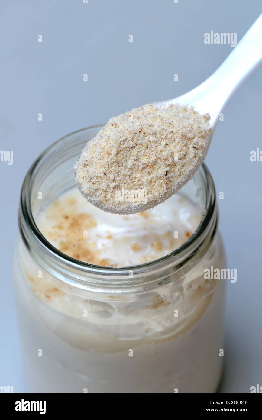 Tigernut flour in spoon and glass yoghurt, Cyperus esculentus Stock Photo
