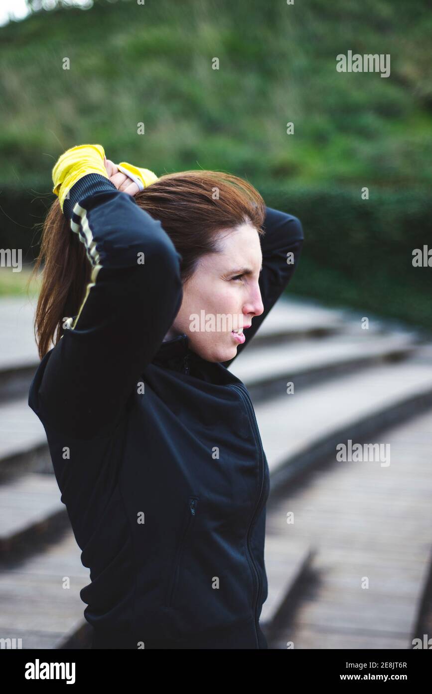 Portrait of young woman in white sportswear behind wood stairs at park. Stock Photo