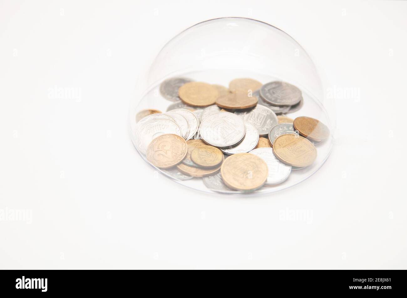 metal coins are grouped under a glass semicircle on a white background Stock Photo