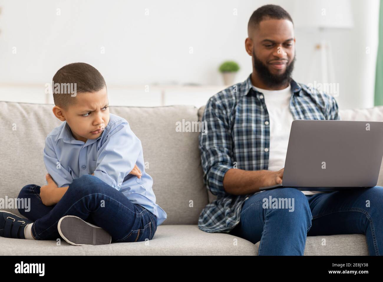 Indifferent Black Father Neglecting Son Using Laptop Sitting At Home Stock Photo