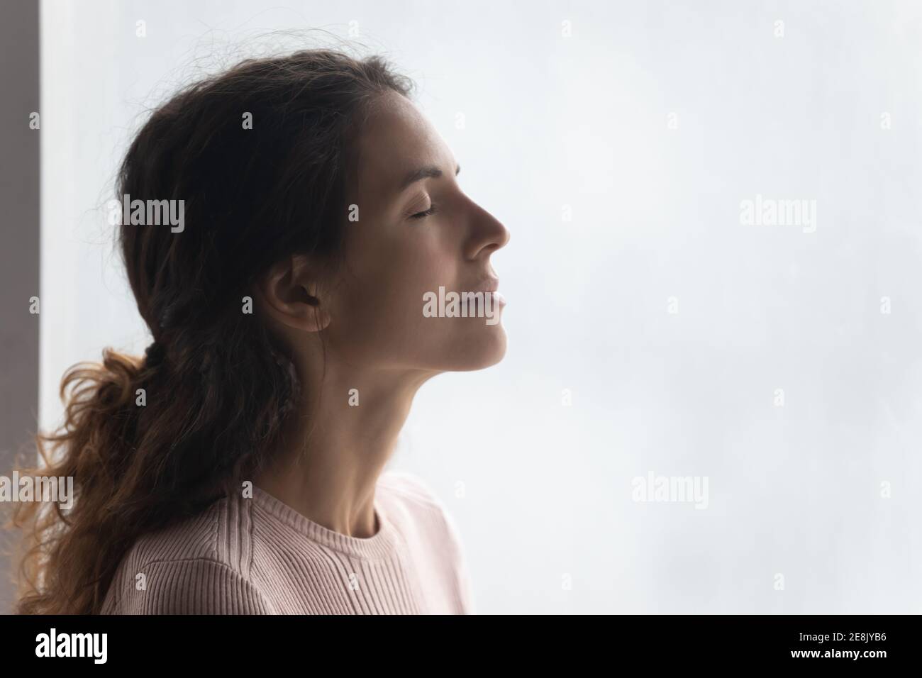Mindful smiling beautiful young woman breathing fresh air. Stock Photo