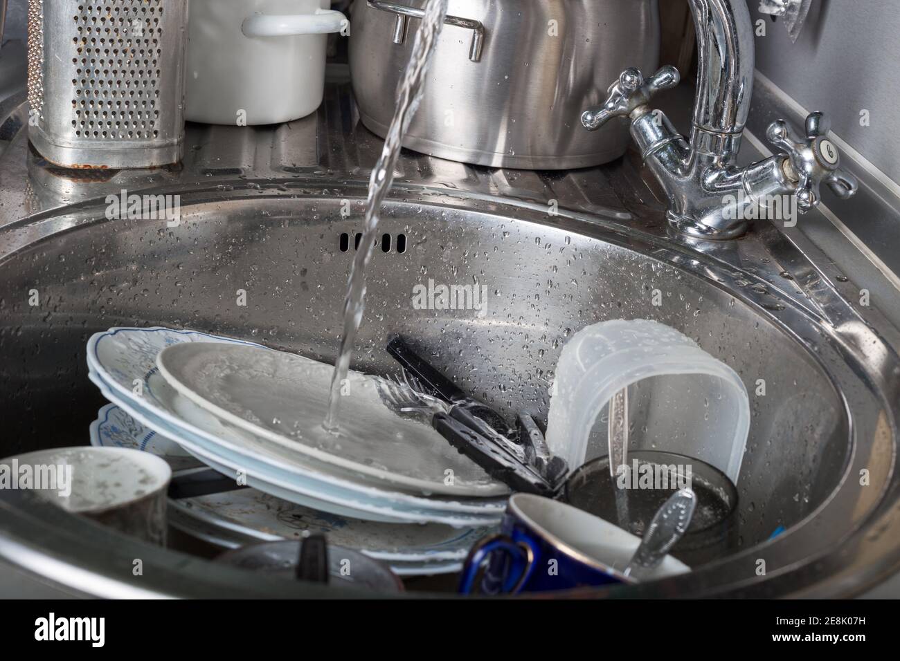 Unwashed dishes and utensils in kitchen sink Stock Photo