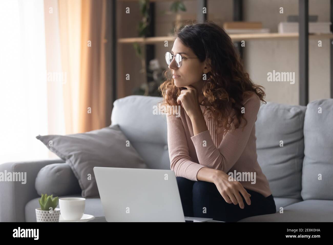 Distracted from online computer work young woman looking in distance. Stock Photo