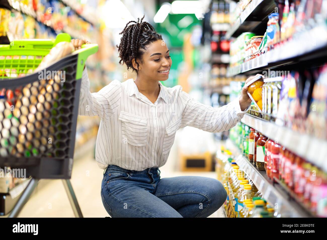 African Woman Choosing Products Doing Grocery Shopping In Supermarket Stock Photo