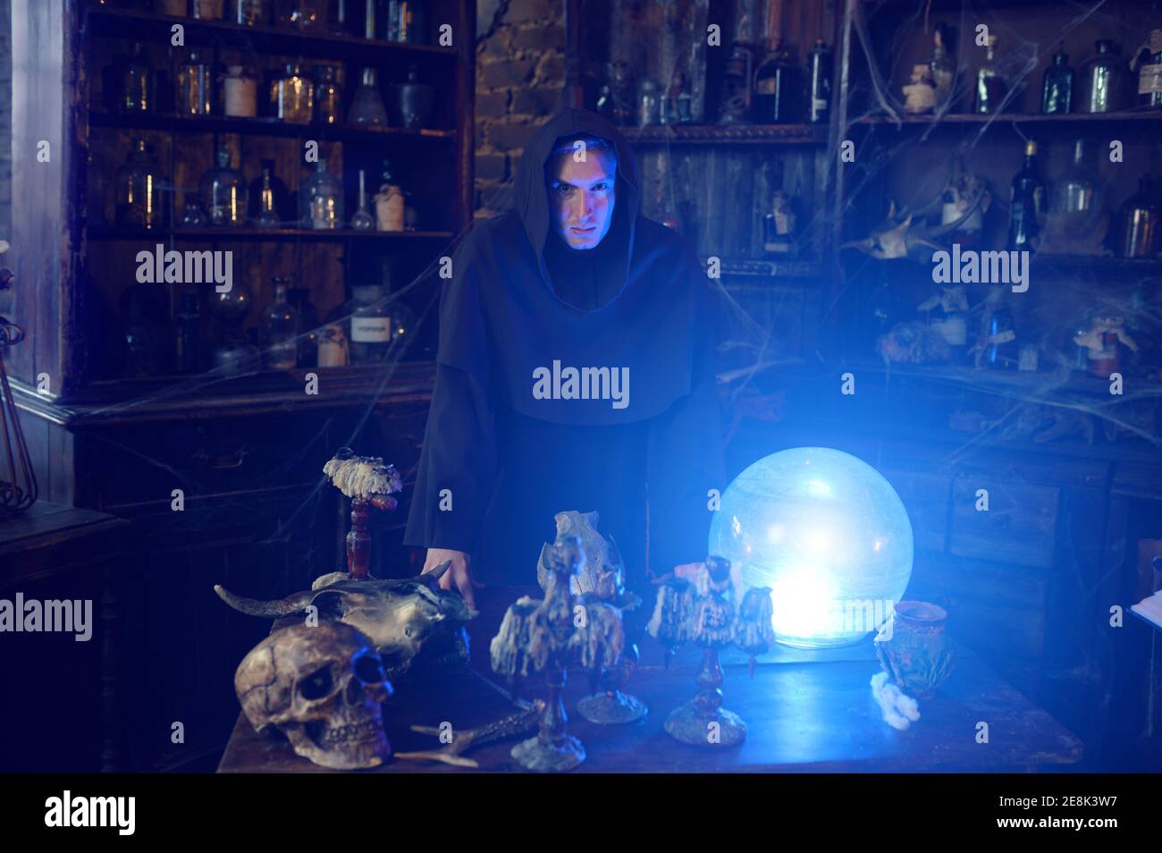 Male exorcist in hood near the magic crystal ball Stock Photo
