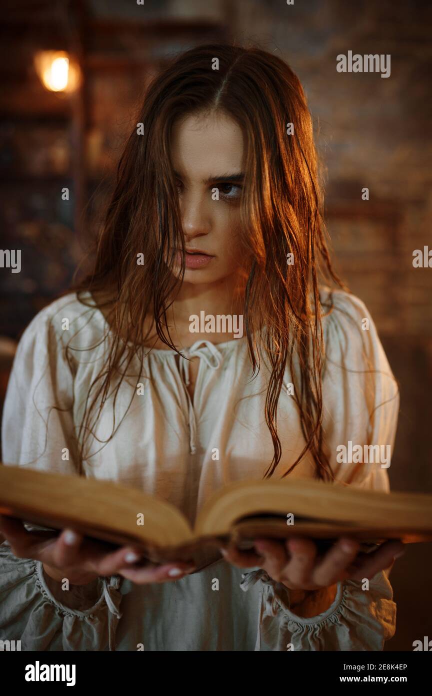 Young demonic woman holds book of spells Stock Photo