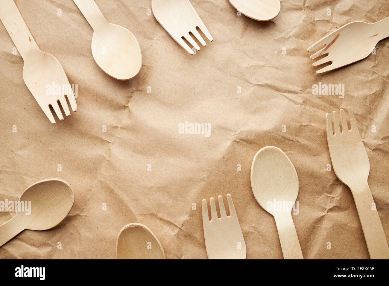 eco friendly disposable kitchenware utensils on paper background. look from above. wooden forks and spoons. eco friendly concept. border frame Stock Photo