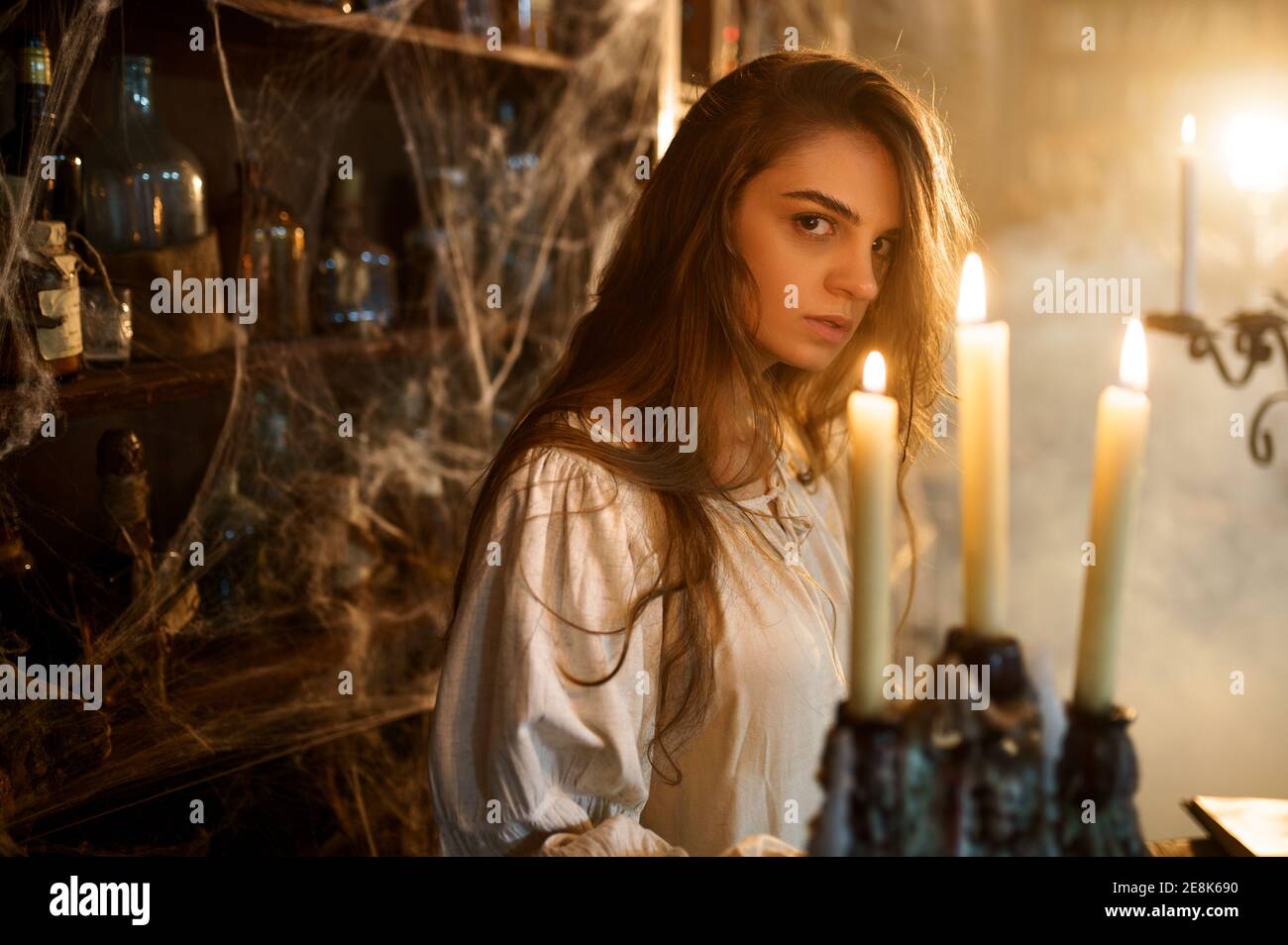 Crazy demonic woman near the shelf with potions Stock Photo