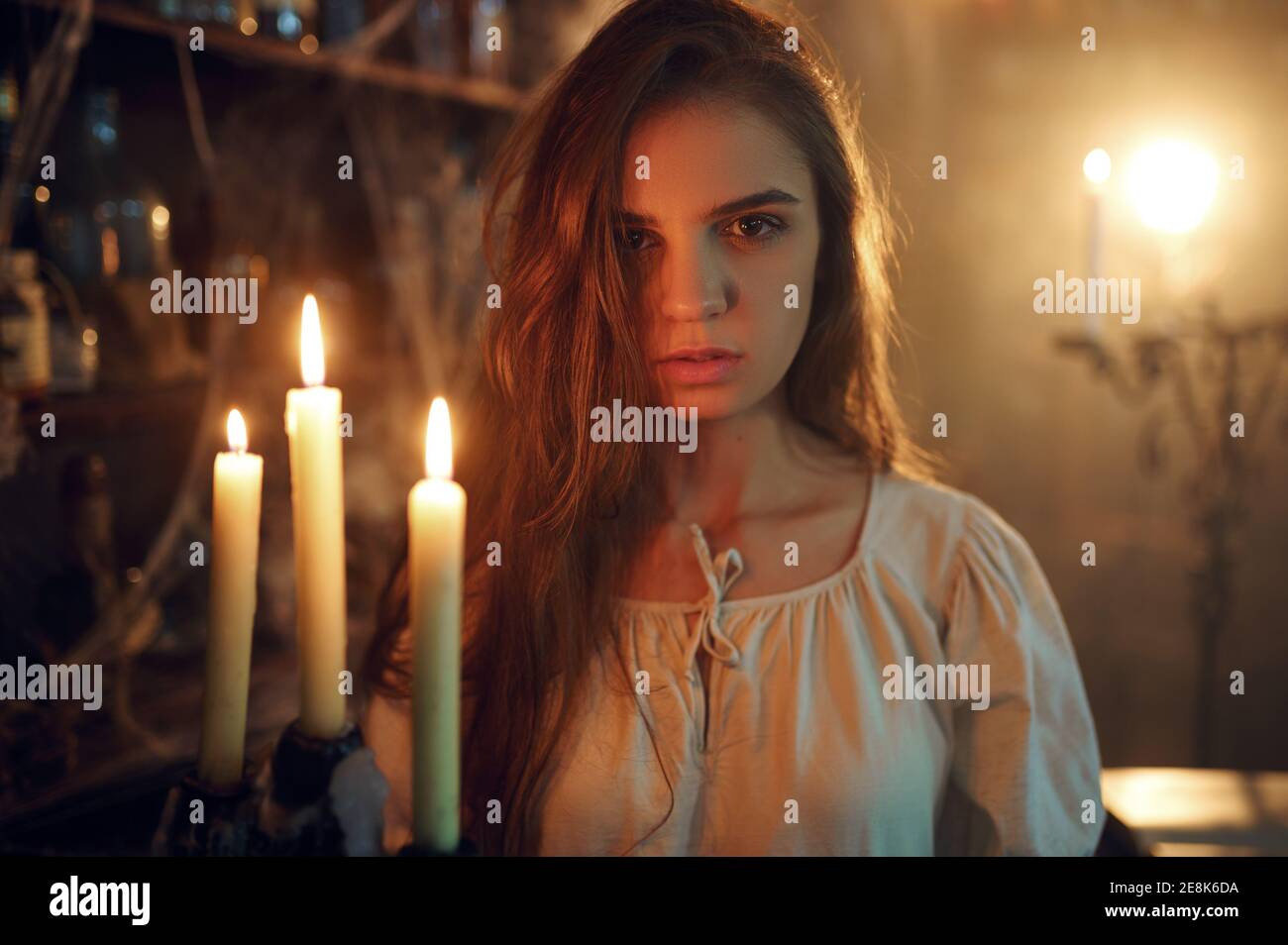 Crazy demonic woman with candle choosing potions Stock Photo